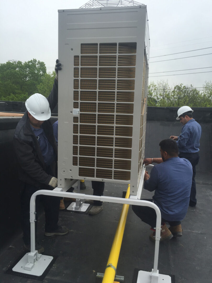 A group of men working on an air conditioner unit.